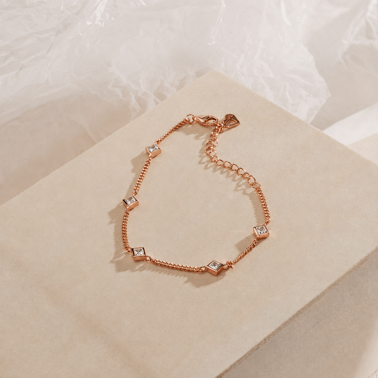 Rose gold bracelet with diamond-like stones on a soft beige surface